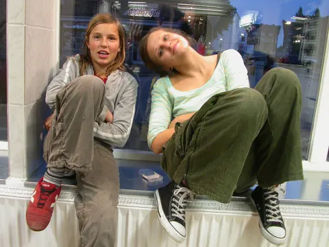 Zwei Mädchen sitzen auf der Fensterbank des neuen Ladens und machen Pause
