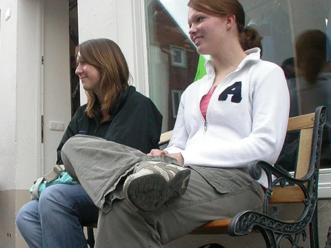 Zwei Frauen sitzen auf einer Bank vor dem Schaufenster