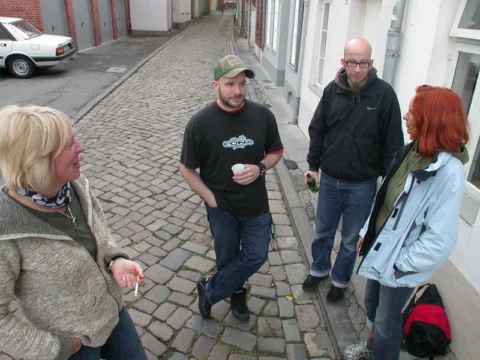 Eine Gruppe steht auf dem Kopfsteinpflaster vor dem Laden