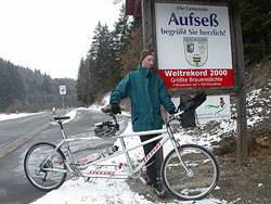 Ein Fahrer mit Mountainbike vor dem Ortsschild von Aufseß im Schnee