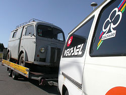 Ein Oldtimer-Transporter auf einem Anhänger hinter einem Kastenwagen