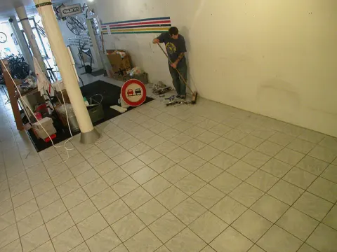 Der alte Laden nach dem Auszug: leerer Fliesenboden, im Hintergrund wird gefegt