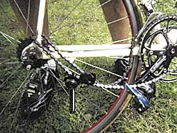 Detail eines Rads: Schaltwerk und Kassette, dahinter Gras