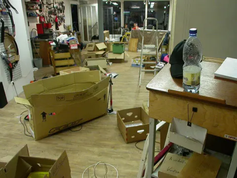 Der halb ausgeräumte alte Laden voller offener Kartons und Werkzeug