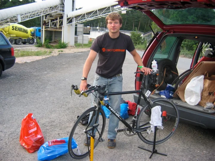Petz im Trikot des at racing team mit seinem Rennrad am geöffneten Kofferraum
