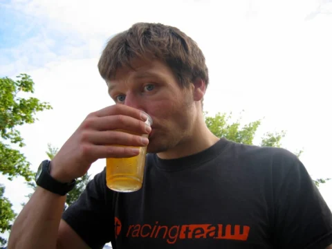 Ein Mann trinkt ein Glas Bier, auf dem Shirt steht „racingteam“