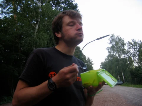 Ein Mann isst aus einer grünen Dose am Straßenrand
