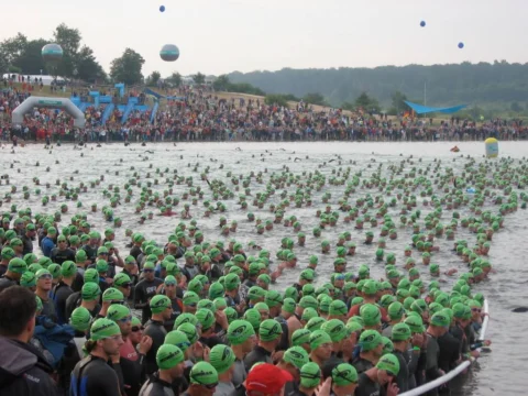 Ein riesiges Feld von Schwimmern mit grünen Badekappen vor dem Start