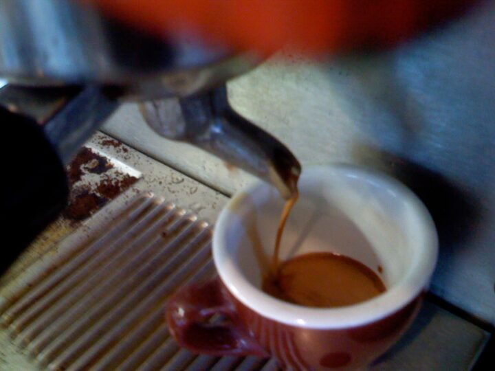 Espresso läuft aus dem Siebträger in eine weiße Tasse