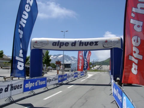 Ein aufblasbarer Zielbogen mit der Aufschrift „Alpe d'Huez“ über einer leeren Straße