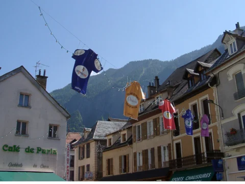 Ein Trikot hängt als Wimpel über einer Dorfstraße vor dem „Café de Paris“