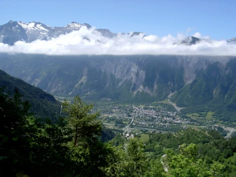 Blick von einem Berghang über ein Tal, dahinter schneebedeckte Gipfel