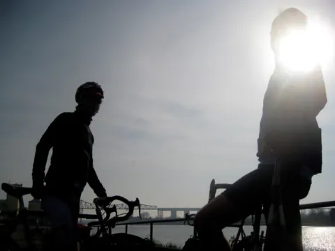 Zwei Radfahrer als Silhouetten gegen die tief stehende Sonne