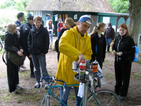 Ein Mann in gelber Regenjacke steht mit seinem Rad in einer Gruppe