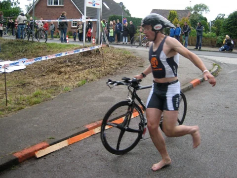 Ein Athlet läuft barfuß mit seinem Rad über die Matte