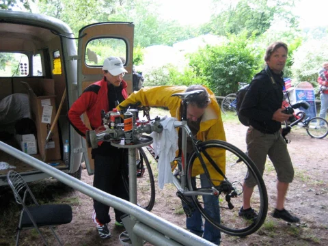 Drei Personen an einem Rad neben dem geöffneten Transporter