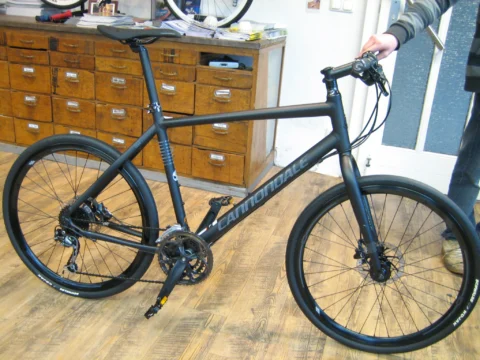 Ein graues Cannondale mit geradem Lenker vor der Schubladenwand