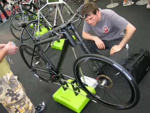 Zwei Männer arbeiten an einem Rennrad im Montageständer auf der Messe