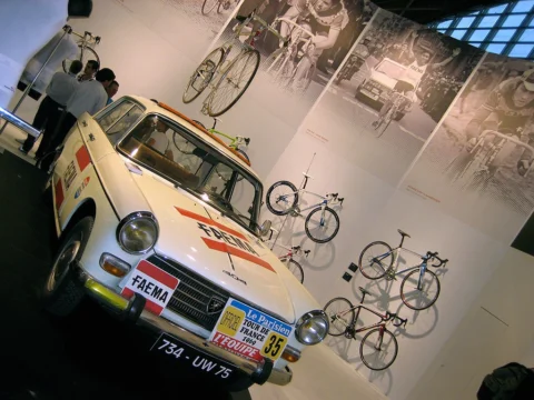 Ein historischer Teamwagen mit Rennrädern auf dem Dach in einer Ausstellung