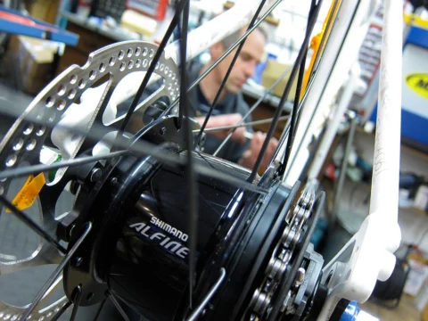 Detail eines Rads: Shimano-Alfine-Nabe im Hinterrad, dahinter ein Mechaniker