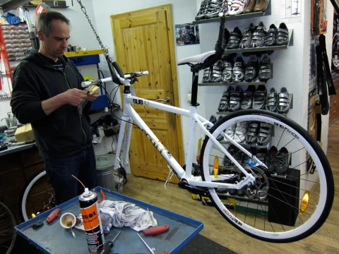 Ein Mechaniker arbeitet an einem weißen Rennrad im Laden