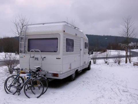 Ein Wohnmobil mit Fahrrädern am Heck steht im Schnee