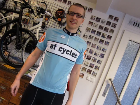 Ein Mann im hellblauen at-cycles-Trikot steht im Laden