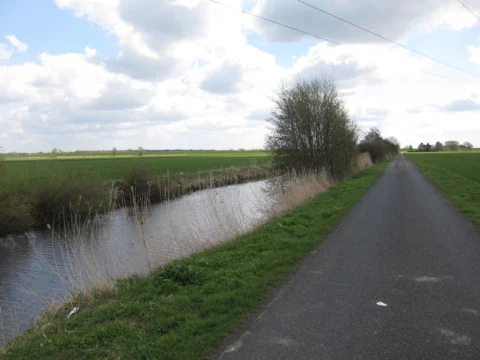 Ein Radweg neben einem Entwässerungsgraben durch flaches Land