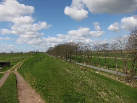 Ein Deich mit parallel laufendem Weg unter Wolkenhimmel