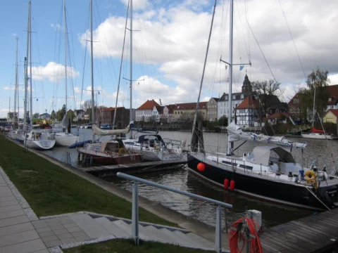 Segelboote in einem Stadthafen, dahinter Giebelhäuser