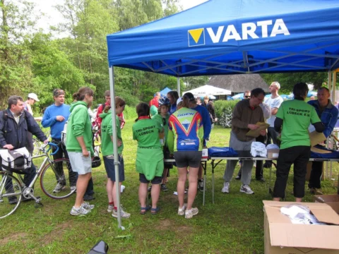 Teilnehmende und Helfer an einem blauen Zelt der Wettkampforganisation