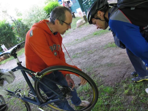 Zwei Männer beugen sich über ein Rennrad und prüfen die Bremse