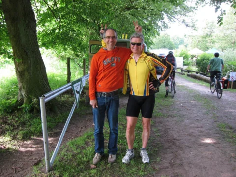Zwei Personen posieren am Wegrand, einer im orangefarbenen Pullover