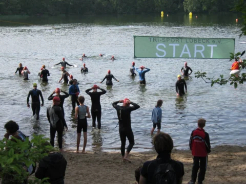 Schwimmer in Neoprenanzügen im Wasser vor einem Startbanner