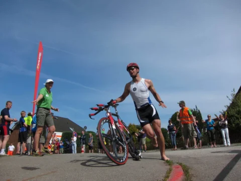 Ein Athlet schiebt sein Rennrad durch die Wechselzone