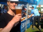 Ein Mann trinkt ein Glas Bier, dahinter eine Absperrung
