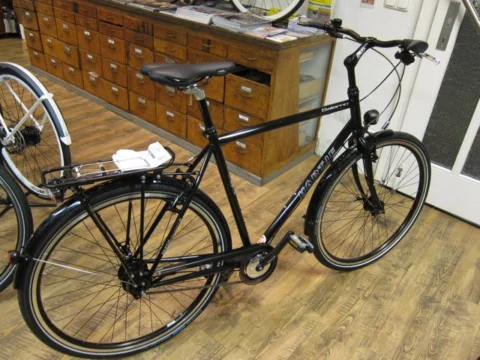 Ein schwarzes Trekkingrad mit Gepäckträger auf dem Holzboden im Laden