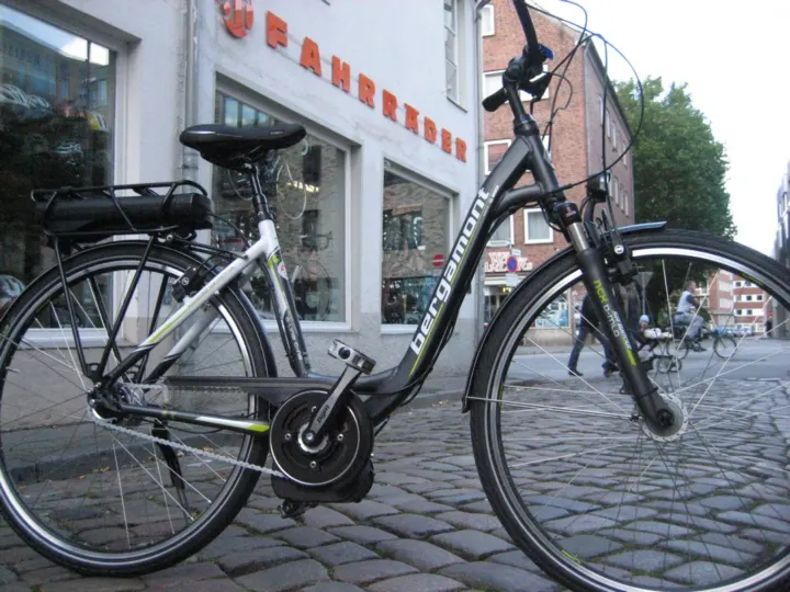 Ein schwarzes Trekkingrad vor der Ladenfront auf Kopfsteinpflaster