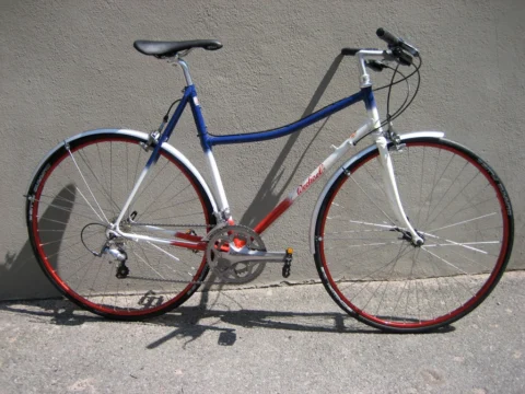 Ein blau-weißes Trekkingrad mit geradem Lenker an einer Wand