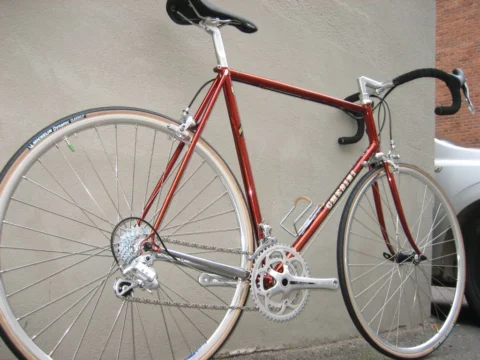 Ein dunkelrotes Chesini-Rennrad von der rechten Seite an einer Wand