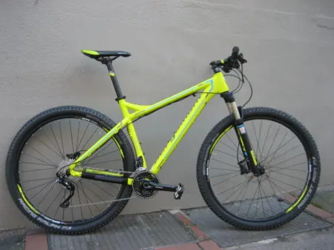 Ein neongelbes Mountainbike von der linken Seite an einer Wand