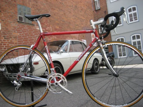Ein rotes Tommasini vor einem cremefarbenen Oldtimer in einer Altstadtgasse