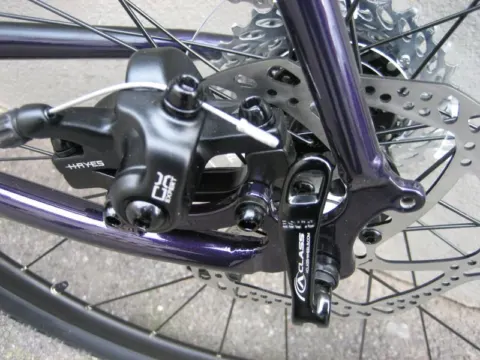 Detail eines violetten Rads: Scheibenbremssattel am Hinterrad