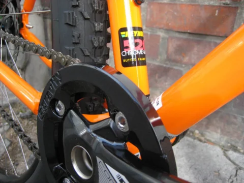 Detail des Kona Unit: Kurbel und Kettenschutz am orangefarbenen Rahmen