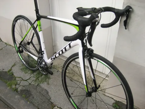 Ein weiß-grünes Scott-Rennrad von vorn an einer Hauswand