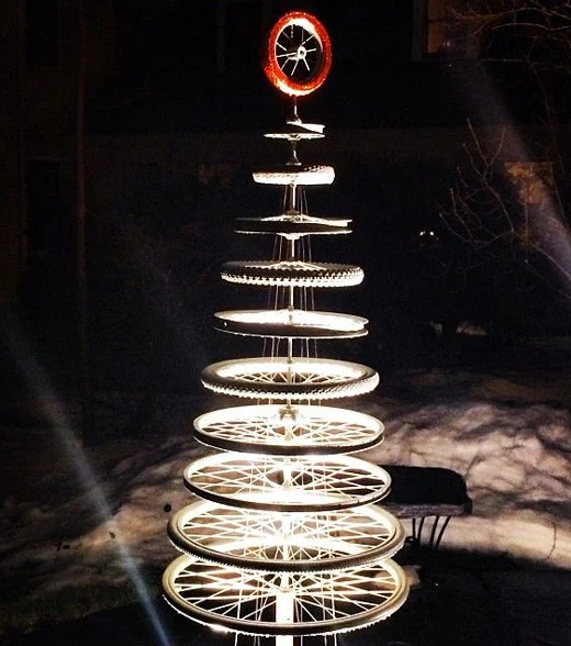 Ein Weihnachtsbaum aus gestapelten Laufrädern, beleuchtet, oben ein rot lackiertes Rad