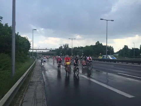Radfahrende auf der leeren Stadtautobahn bei bedecktem Himmel