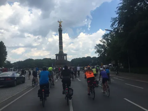 Ein Pulk Radfahrender rollt auf die Siegessäule zu