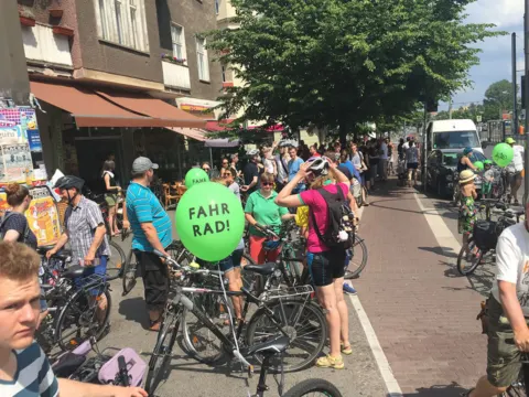 Dicht gedrängte Teilnehmende der Sternfahrt, eine hält einen grünen Ballon mit „Fahr Rad!“