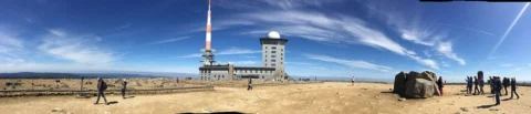 Panorama einer kahlen Bergkuppe mit Sendeturm und Gebäude unter weitem Himmel
